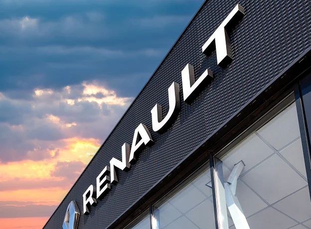 Enseigne RENAULT blanche sur façade noire, soleil couchant et ciel nuageux à Brou en Eure-et-Loir 28