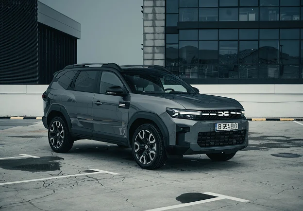SUV Dacia gris garé sur un parking avec un bâtiment moderne en arrière-plan à Brou en Eure-et-Loir 28