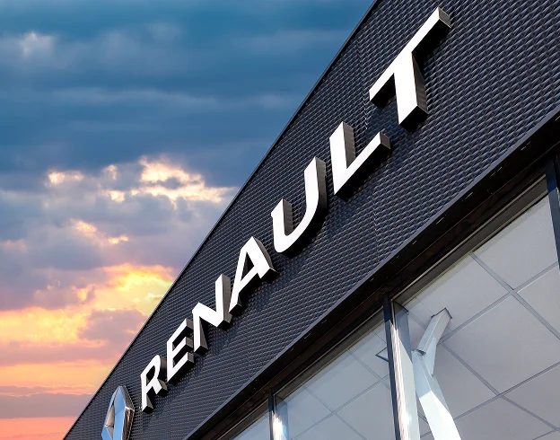 Enseigne RENAULT blanche sur un bâtiment gris texturé, ciel nuageux au coucher du soleil à Brou en Eure-et-Loir 28