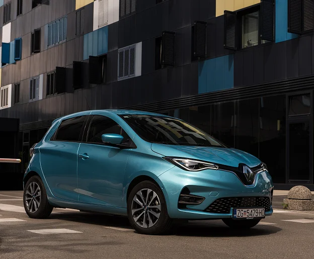 Renault Zoe électrique bleu sarcelle garée devant un immeuble moderne à Brou en Eure-et-Loir 28